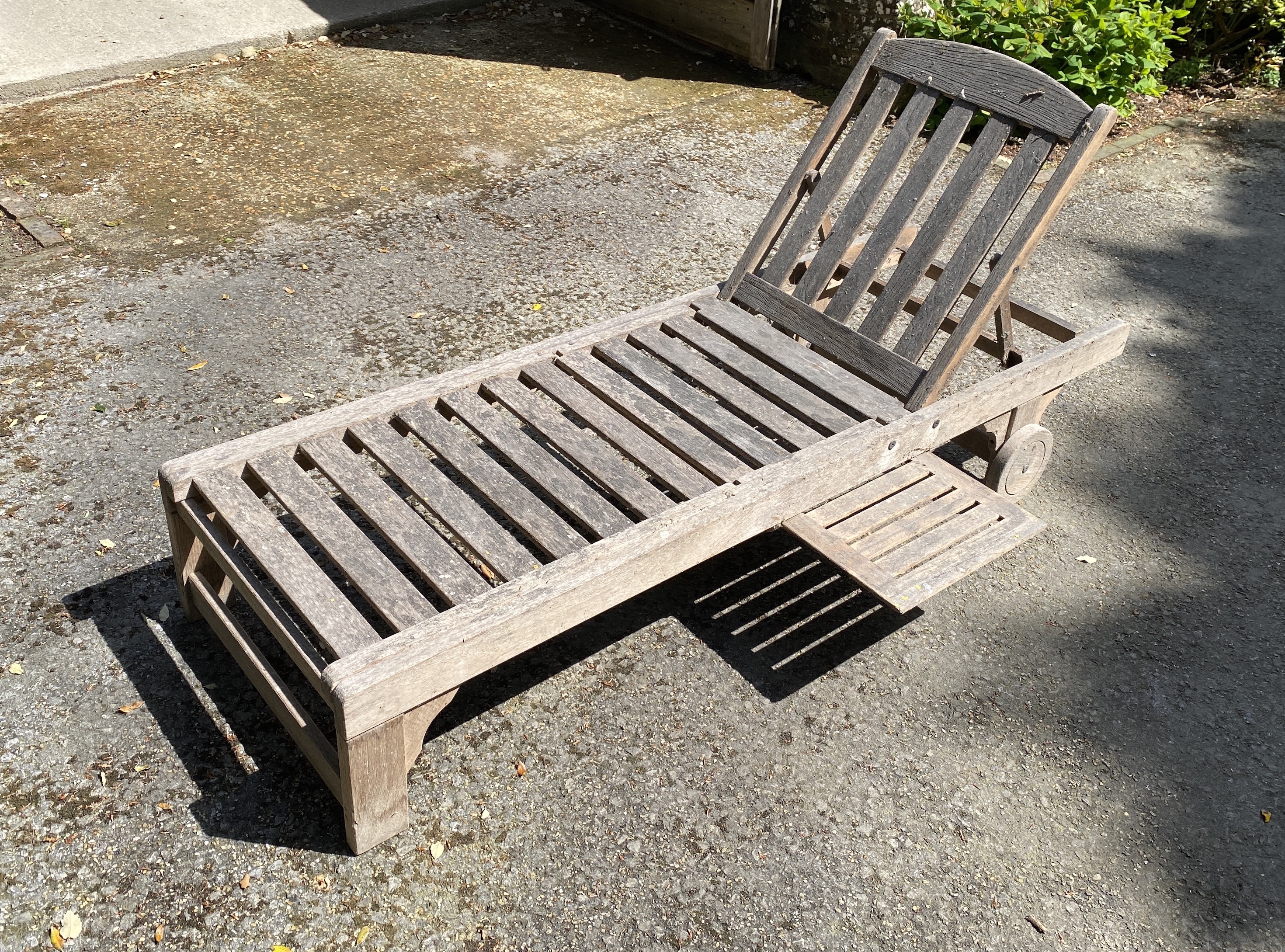 Four slatted teak sun beds, with adjustable backs and integral sliding tables, on two wheels